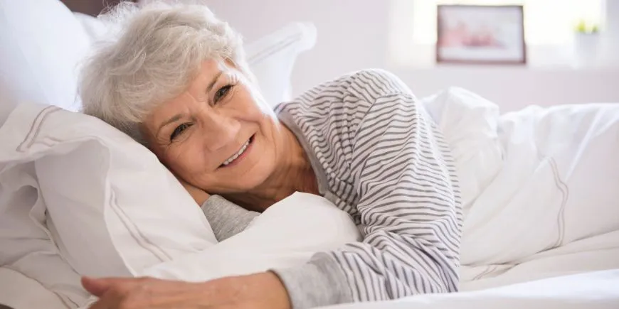 Mujer anciana sonriendo en una cama